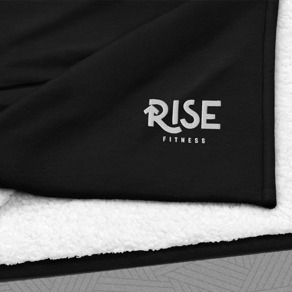 Black and white fleece blanket folded showing the white Rise Fitness logo in the corner.