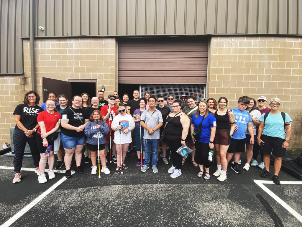 A group of athletes and volunteers posing outside of a gym.