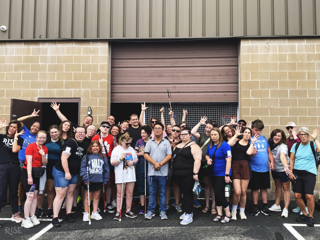 A group of athletes and volunteers posing outside of a gym.