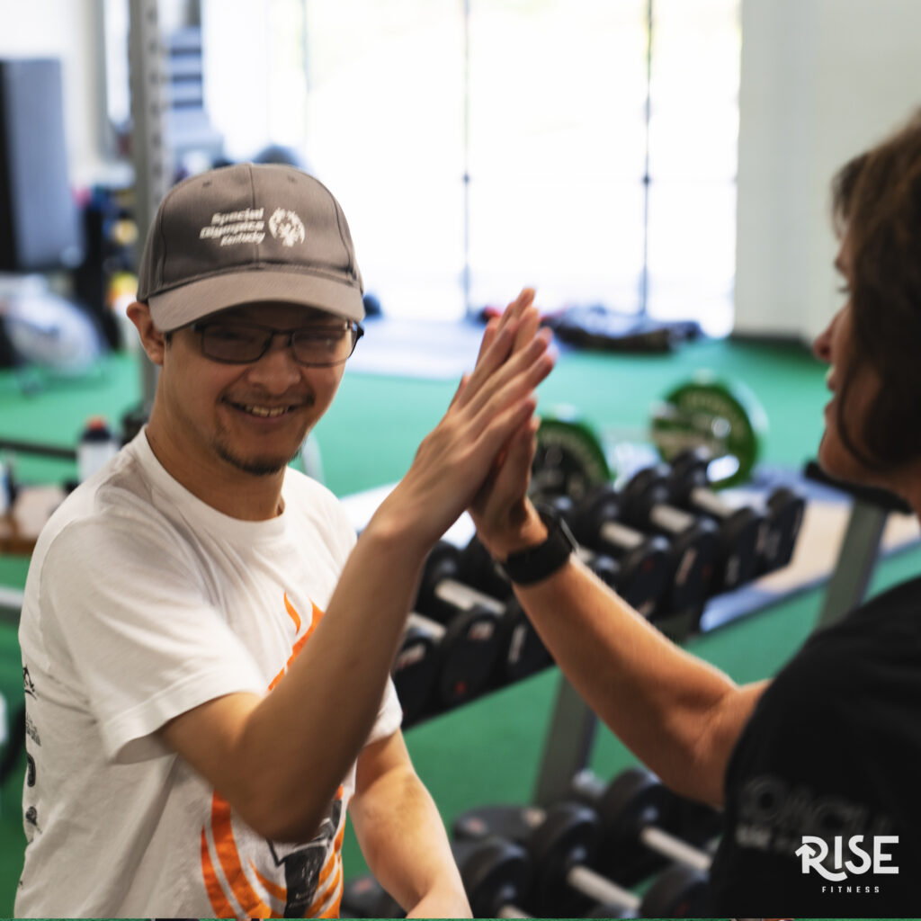 A smiling young male athlete high fives a coach