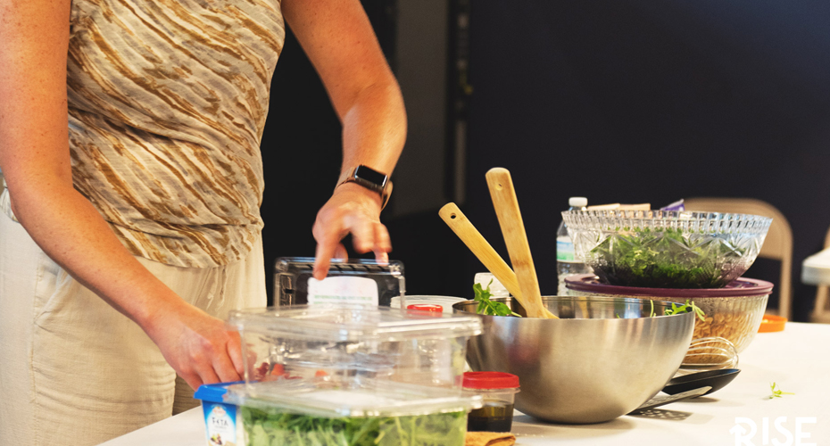 A table with various cooking utensils and items used to make a salad.