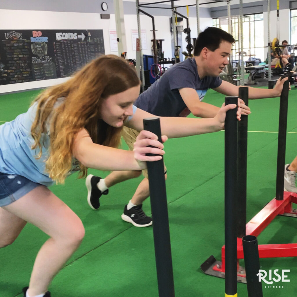 A young female and young male athlete pushing prowlers, racing next to each other.